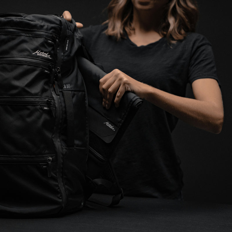 Woman putting Laptop base layer in backpack