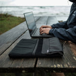Man outside on laptop with Laptop base layer beside him