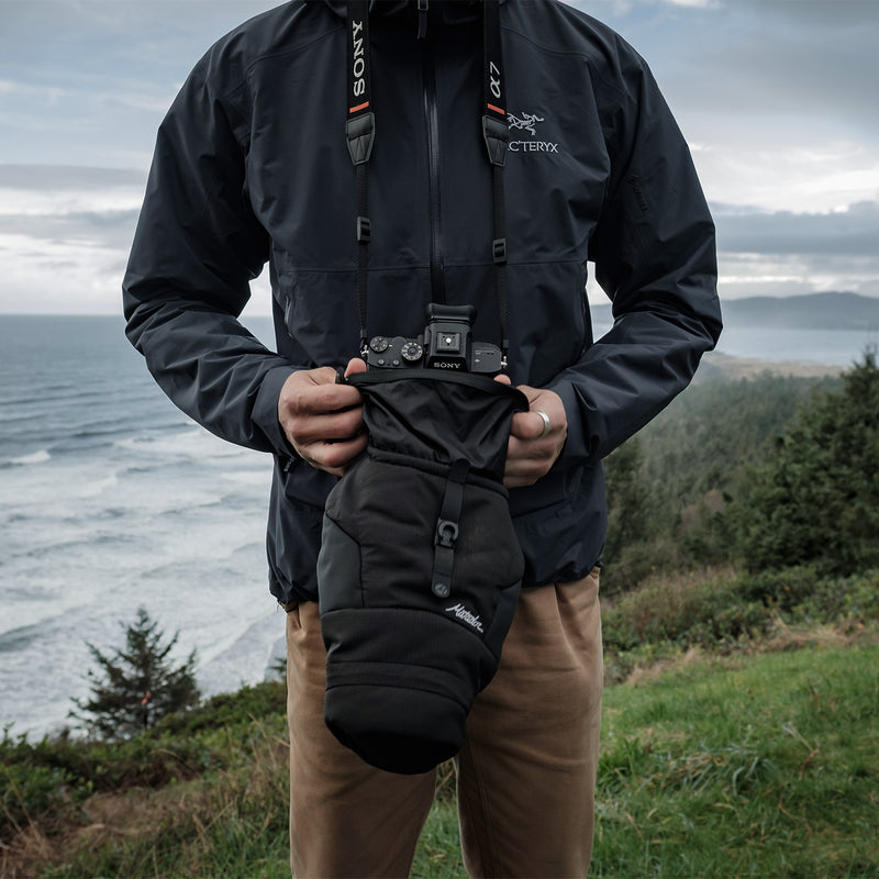 Man by ocean placing camera into base layer