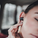 Close up view of woman putting earplug in ear