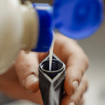 Close up view of shampoo being poured into FlatPak Toiletry Bottle opening