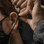 Close up view of man cinching face mask ear strap