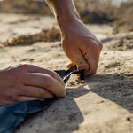Man staking pocket blanket into sand