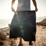 Man at sunset beach, flapping open pocket blanket