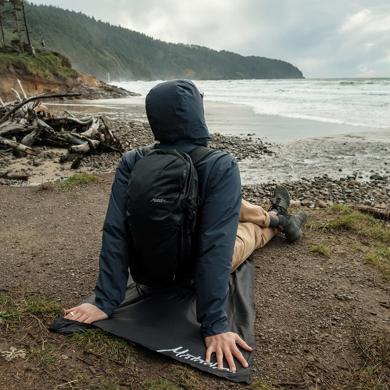 Man looking out at beach, sitting on pocket blanket