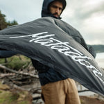 Man on beach throwing open pocket blanket