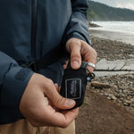 Man on beach, pulling pocket blanket out of pouch